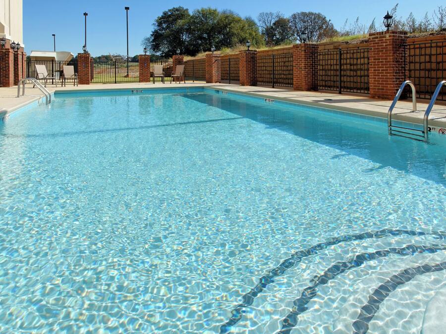 A clear swimming pool with a brick wall and metal railings.