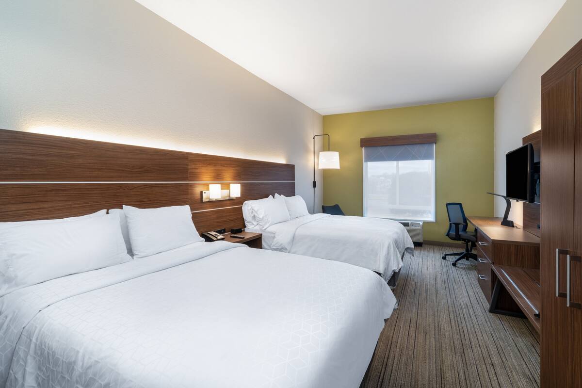 Une chambre d’hôtel avec deux lits, un bureau, une chaise, une télévision et une fenêtre donnant sur un paysage agréable.