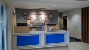 A reception desk with a modern design, featuring a large blue panel and a digital screen displaying the hotel's name. - Holiday Inn Express Hotel & Suites Talladega by IHG (Talladega)