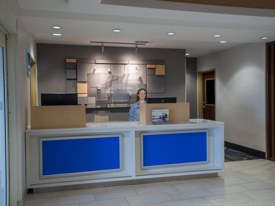 A reception desk with a modern design, featuring a large blue panel and a digital screen displaying the hotel's name.