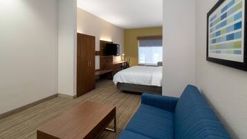 A hotel room with a bed, a sofa, a desk, a TV, and a window.