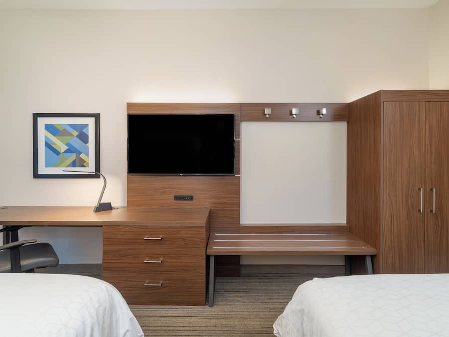 Habitación de hotel con escritorio de madera, televisión de pantalla plana, cama y armario.