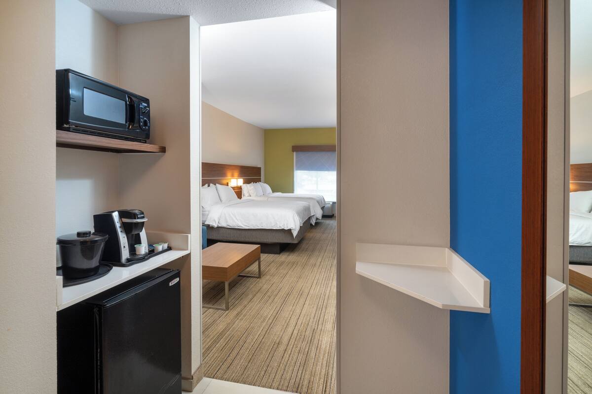 Une chambre d’hôtel équipée d’une kitchenette, d’un lit, d’une table de chevet et d’une grande fenêtre.