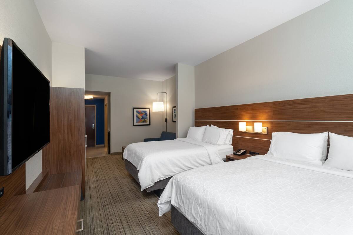 Une chambre d’hôtel avec deux lits, une télévision, un bureau et une lampe.
