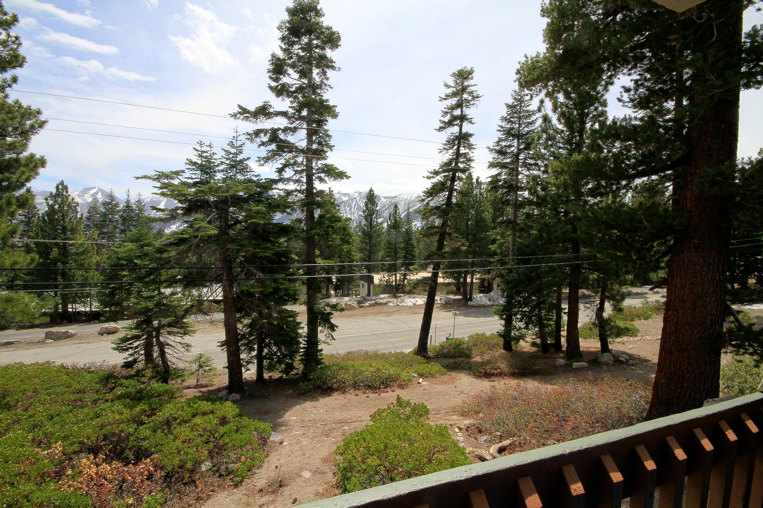 A view of a parking area surrounded by trees and a mountain range in the background.