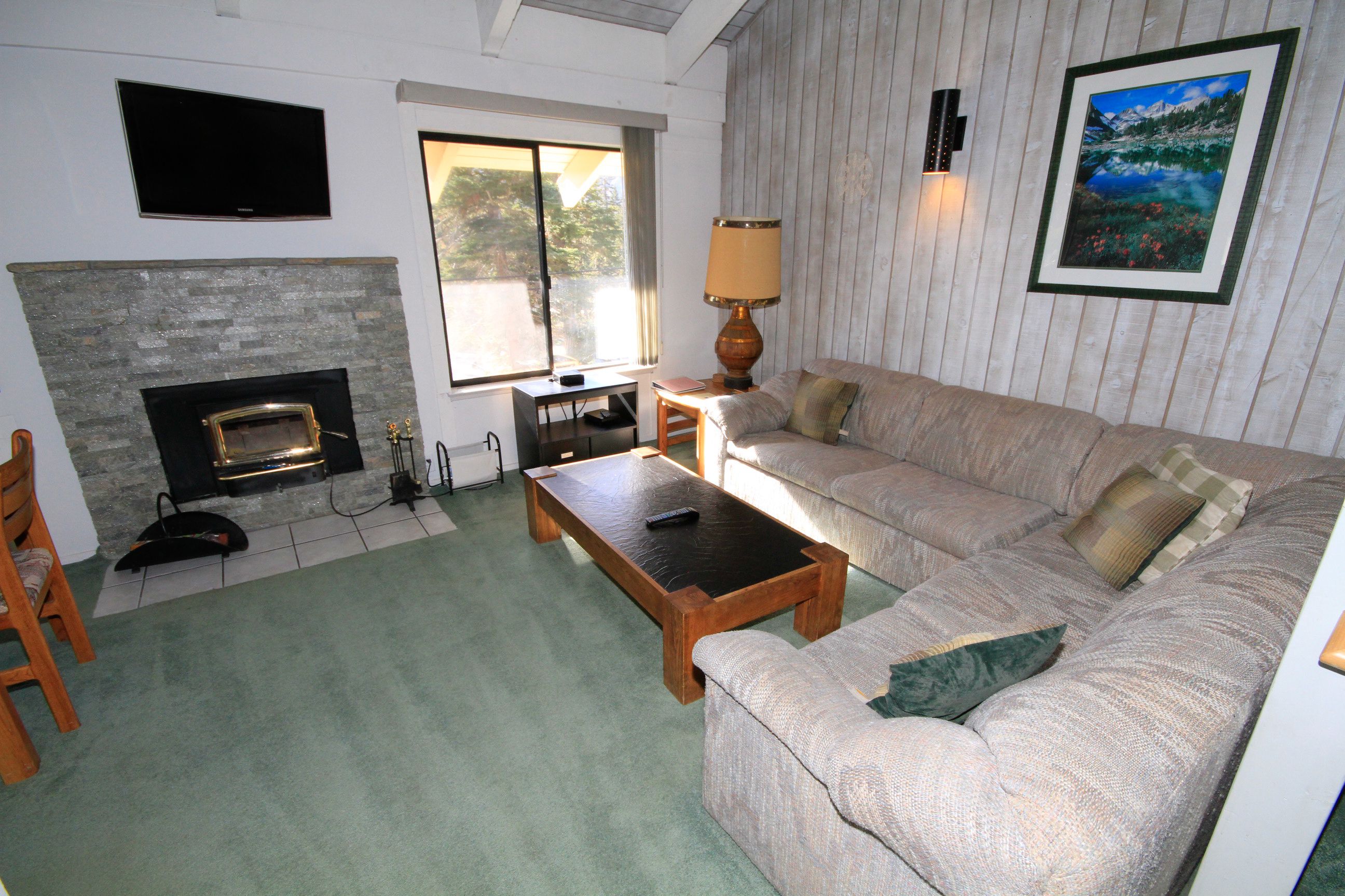 A living room with a fireplace, a sofa, a coffee table, and a TV mounted on the wall.