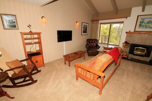 A cozy living room with a fireplace, wooden furniture, and a television.