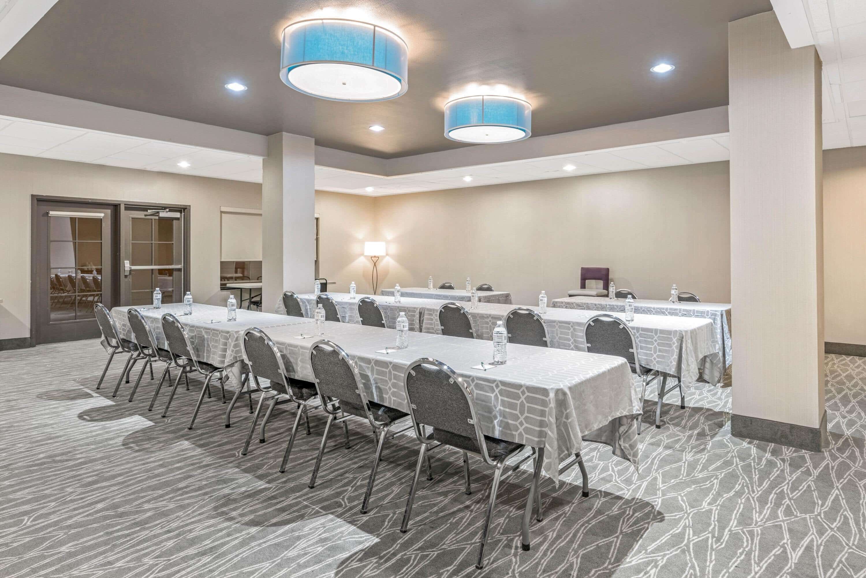 Une salle de conférence avec de longues tables, des chaises et un éclairage au plafond.