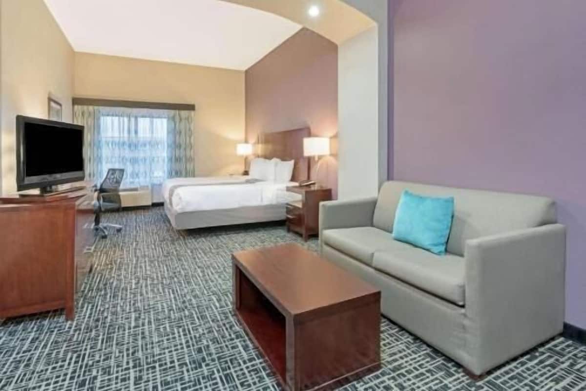 A hotel room with a bed, a sofa, a TV, and a desk.