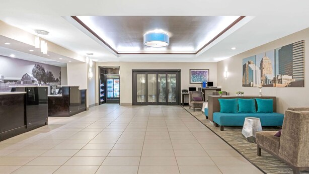 A spacious hotel lobby with a reception desk, a blue sofa, and a patterned rug. - La Quinta Inn & Suites by Wyndham Oklahoma City -Yukon (Yukon)