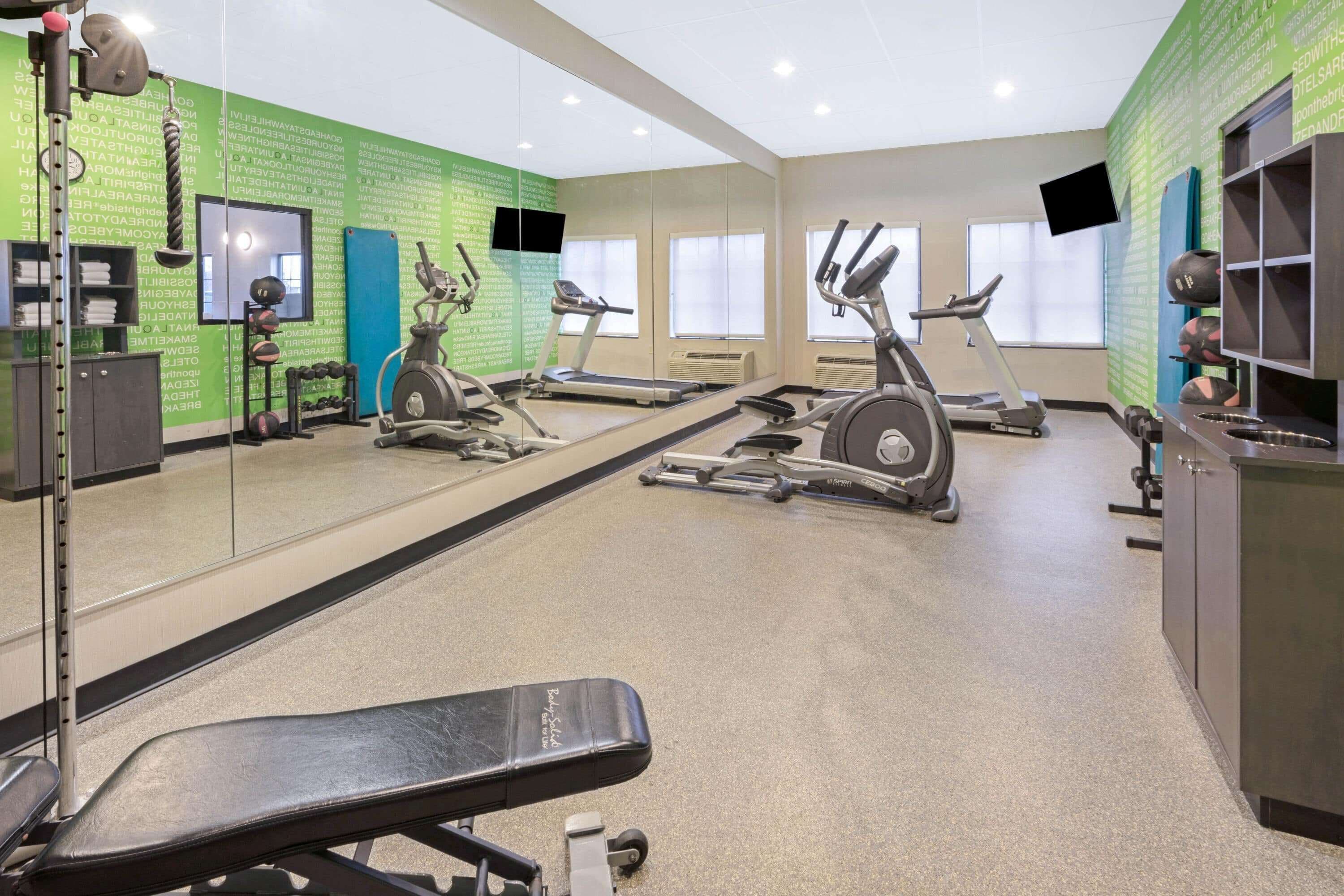 Una palestra con tapis roulant, cyclette e panca per pesi.