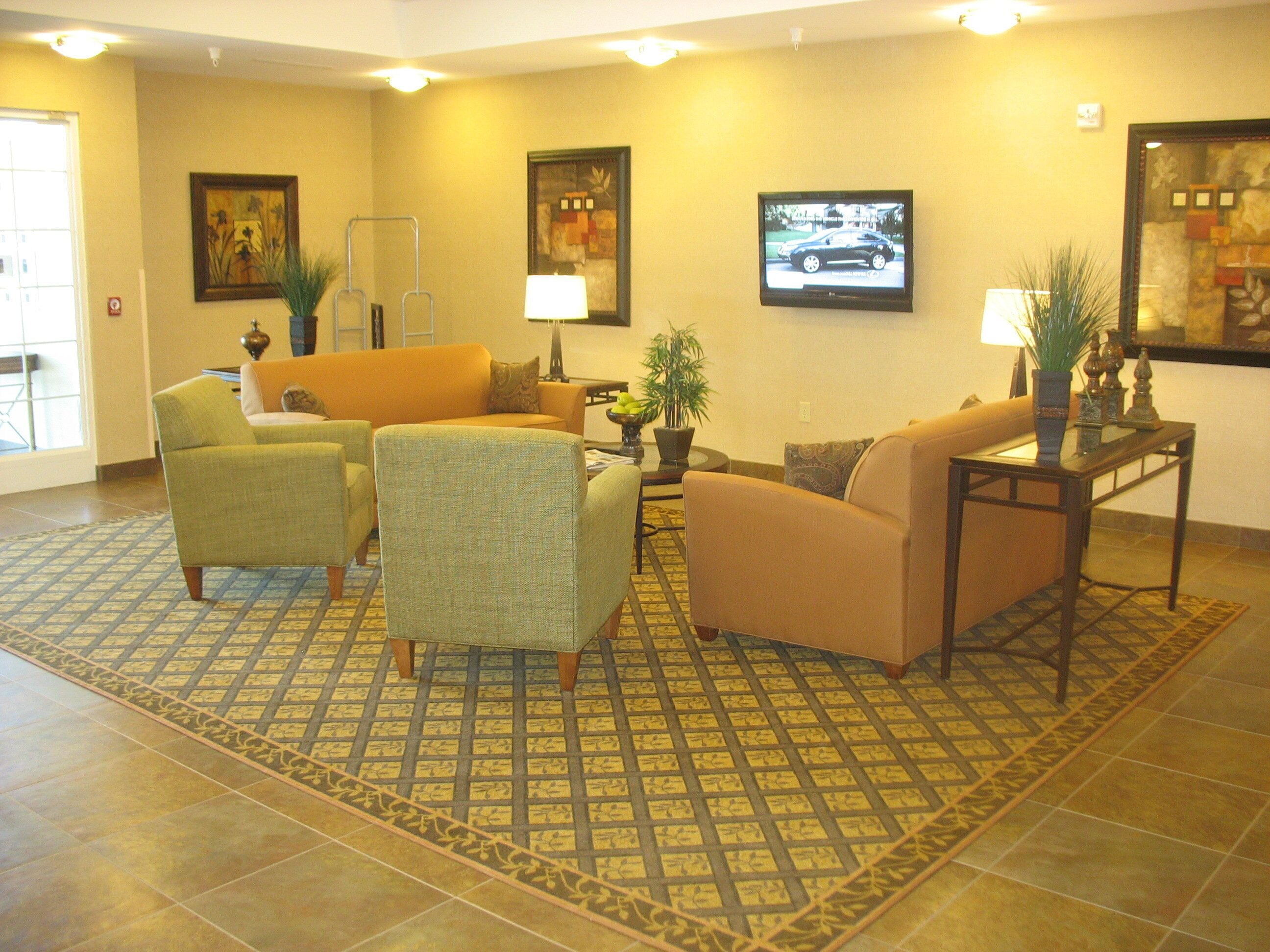 A hotel lobby with a seating area, a television, and artwork on the walls.