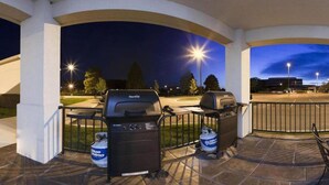 En uteplats med två grillar, ett bord och en vattenautomat.