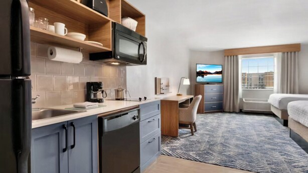 Une chambre d’hôtel équipée d’une kitchenette, d’un lit, d’un bureau et d’une télévision.