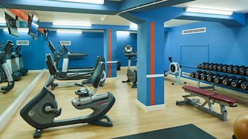 Uma academia com equipamentos de ginástica, um banco e uma barra de halteres.