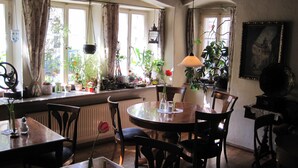 Een eethoek met een ronde tafel, stoelen, een hanglamp en verschillende potplanten.