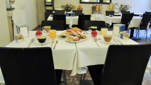 A breakfast setting with tables, chairs, and a TV in the background. - Florida rooms - comfort Hotel (Rome)