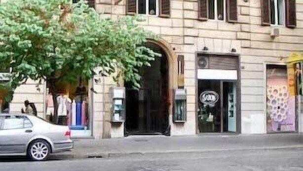 A building with a classic architectural style, featuring a central entrance with a black door, multiple windows with shutters, and a small balcony above the entrance. - Florida rooms - comfort Hotel (Rome)