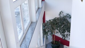 A staircase with a potted tree, white walls, and red accents. - Hotel Wasserburg (Munich)
