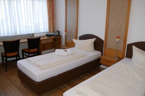 Une chambre d’hôtel comprenant un lit, un bureau, deux chaises, une table de chevet et une lampe.