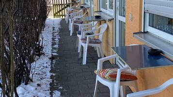 Eine Reihe aus weißen Plastikstühlen und -tischen an einem befestigten Weg mit Schnee.