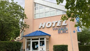 A hotel entrance with a blue awning, a sign reading "HOTEL WASSERBURG", and a wheelchair-accessible entrance. - Hotel Wasserburg (Munich)