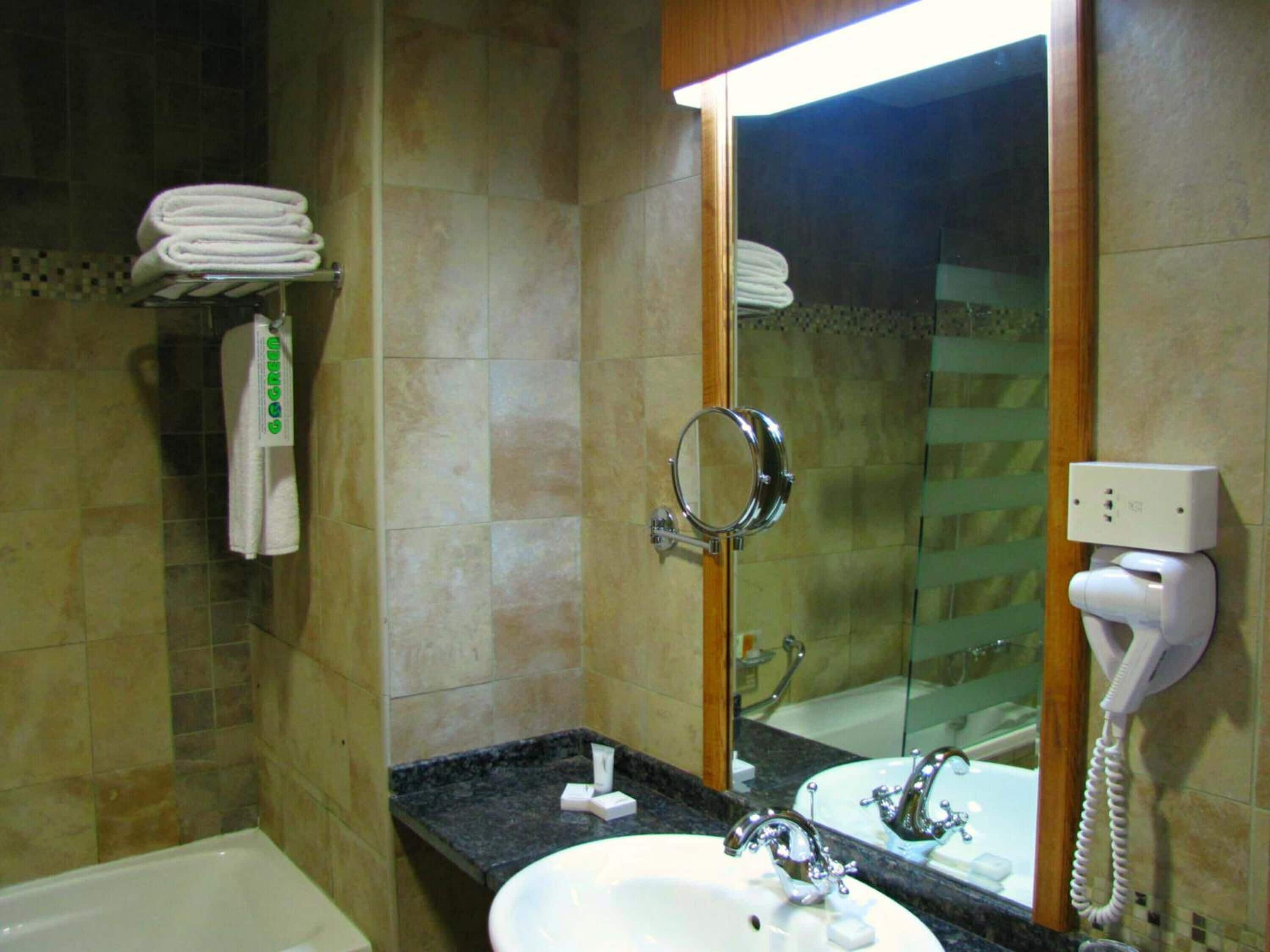 A bathroom with a sink, mirror, and towel rack.
