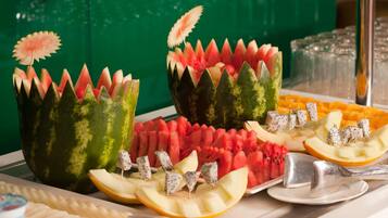 A buffet with various fruits and vegetables, including watermelon and apple slices, arranged on a table.