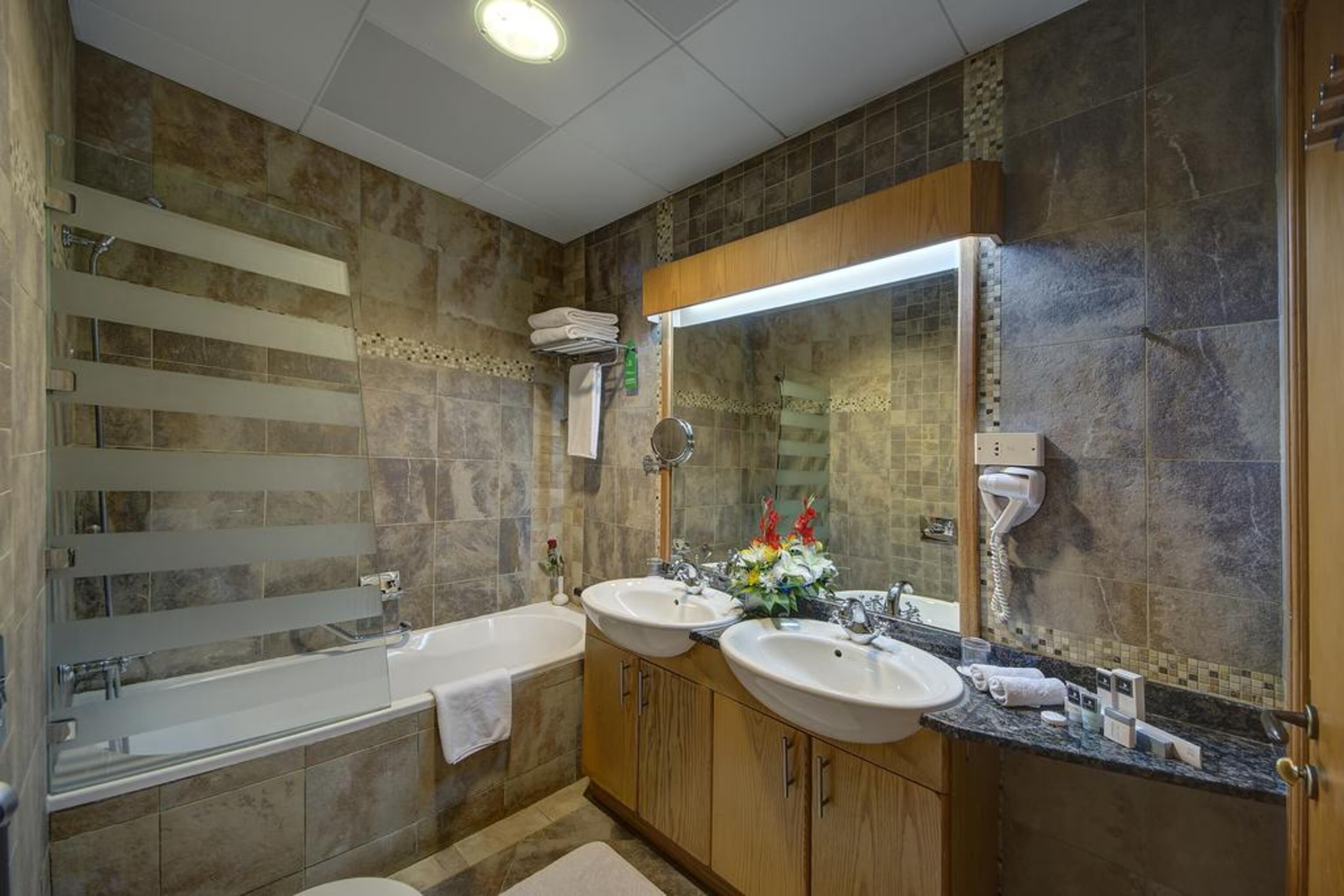 Ein Badezimmer mit zwei Waschbecken, einer Badewanne und einem großen Spiegel.