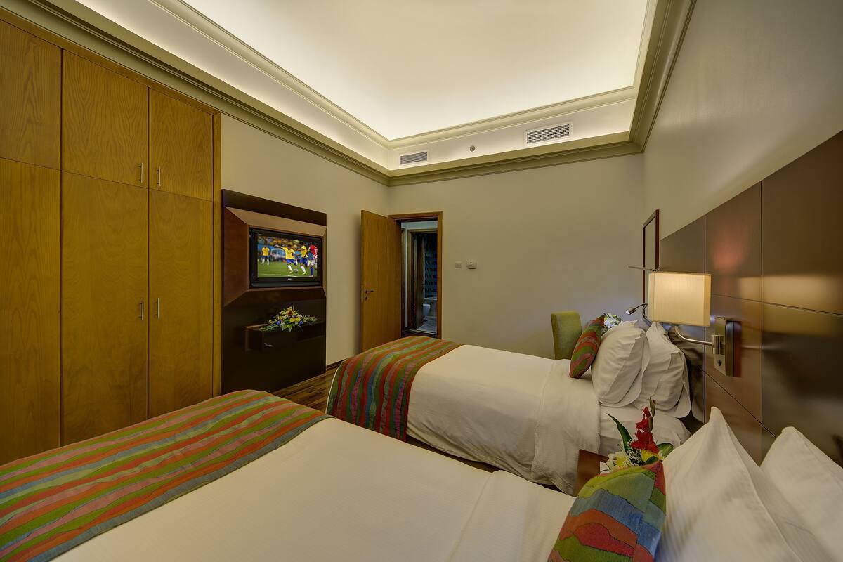 A hotel room with two beds, a television, and a wardrobe.