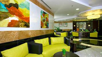 A lobby with yellow sofas, a reception desk, and abstract art on the walls.