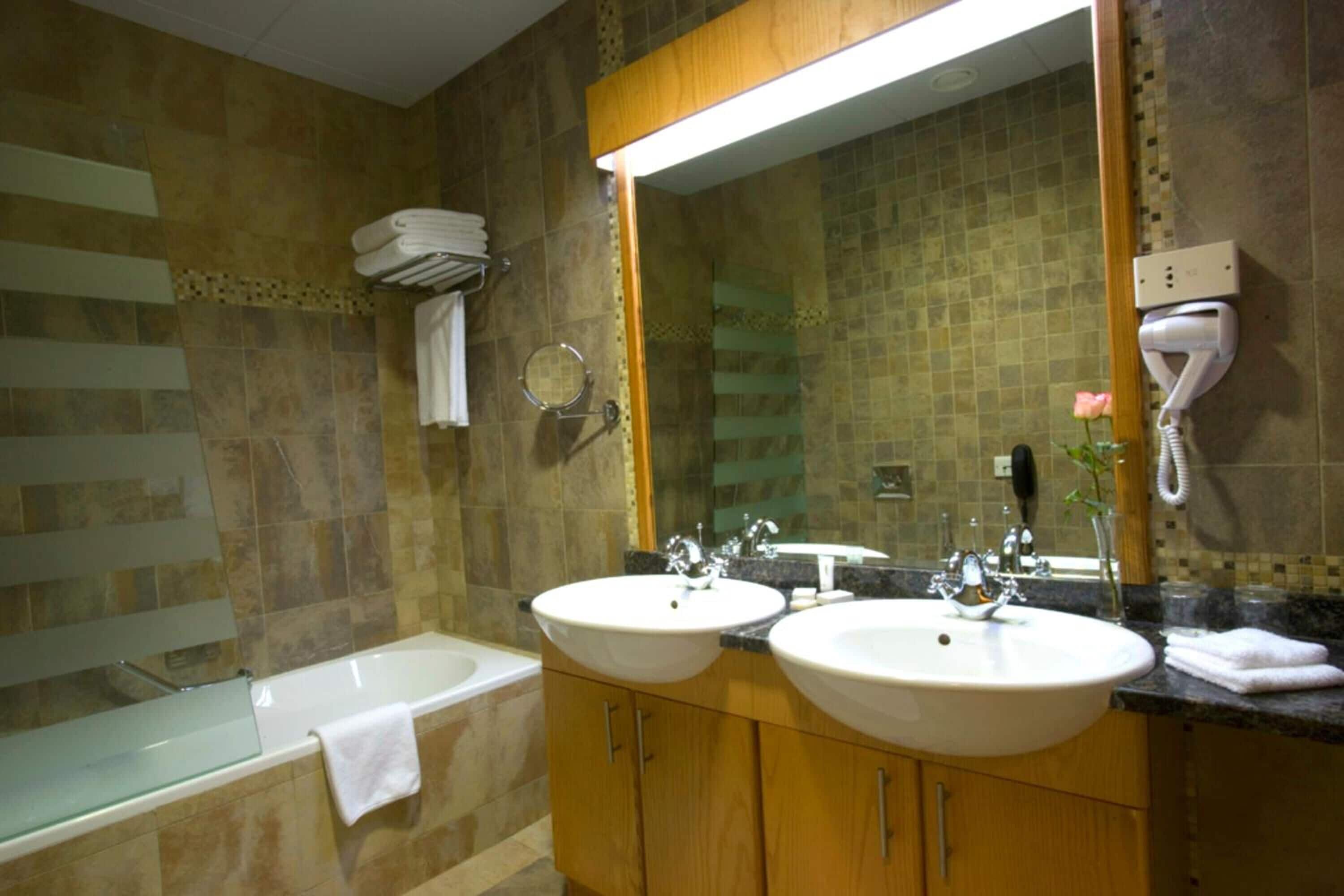 A bathroom with two sinks, a bathtub, and a large mirror.