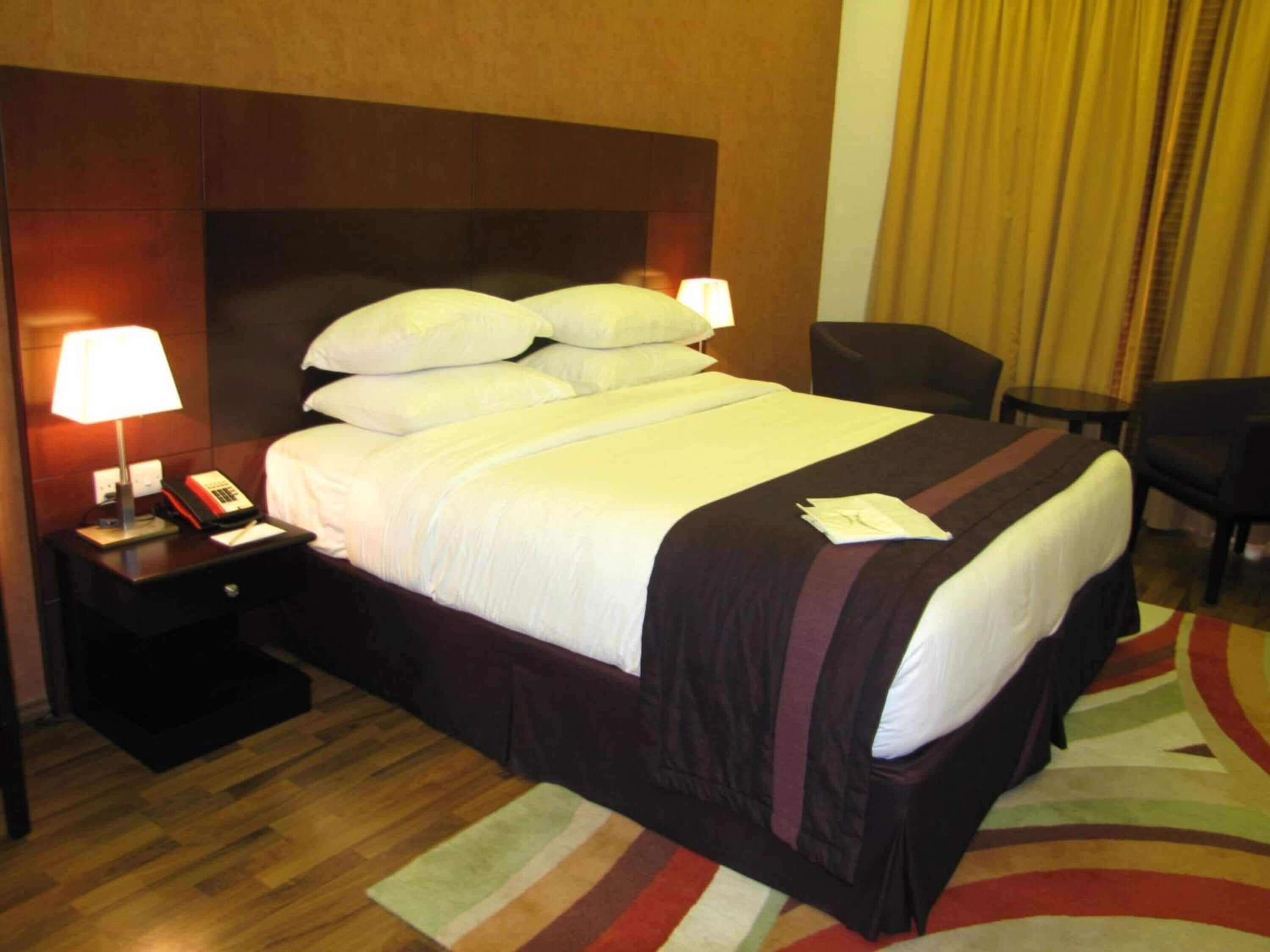 Ein Hotelzimmer mit einem großen Bett, zwei Nachttischen, einem Schreibtisch und einem Stuhl.