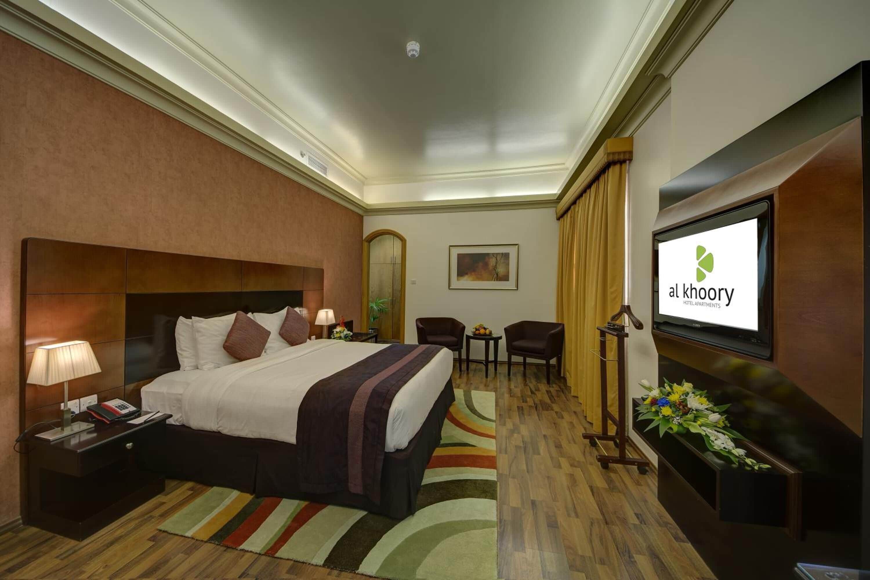 A hotel room with a bed, bedside tables, a TV, a desk, and a chair.