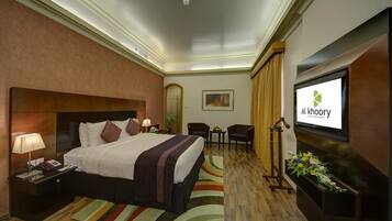 A hotel room with a bed, bedside tables, a TV, a desk, and a chair.