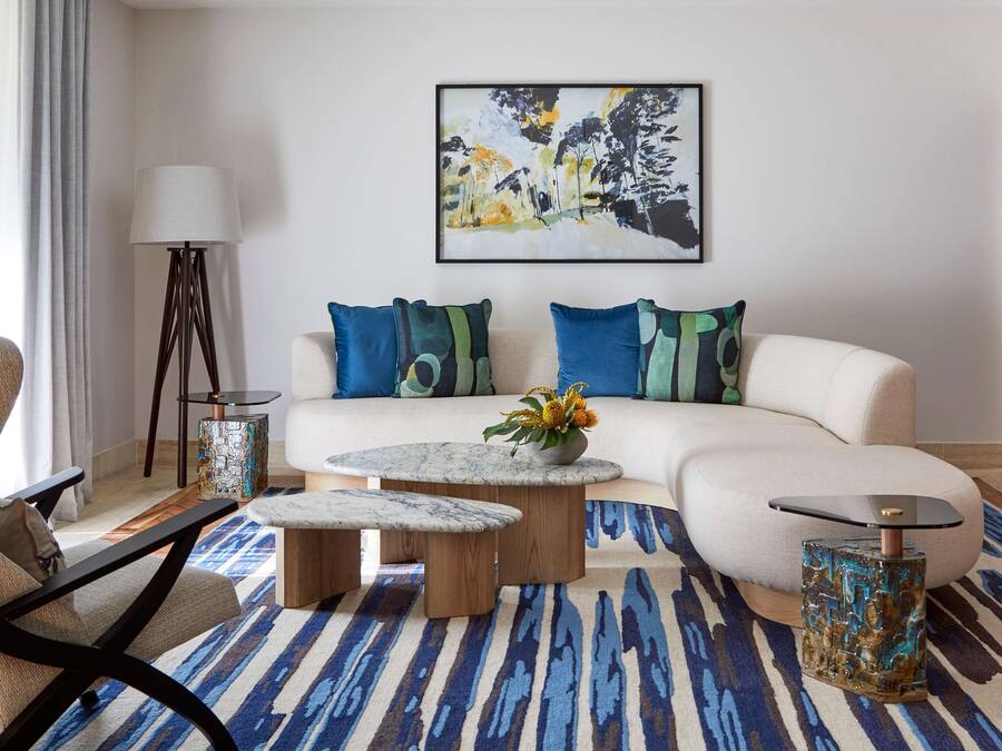 Un salon moderne avec un canapé d’angle, une table basse ronde, une table d’appoint et un lampadaire.