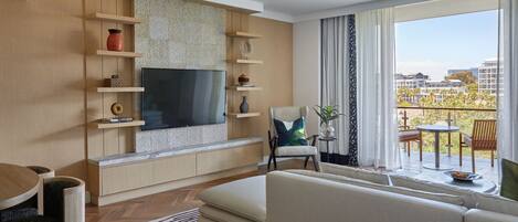 Una sala de estar moderna con un televisor de pantalla plana grande, estanterías empotradas, un sofá y un comedor con mesa y sillas.
