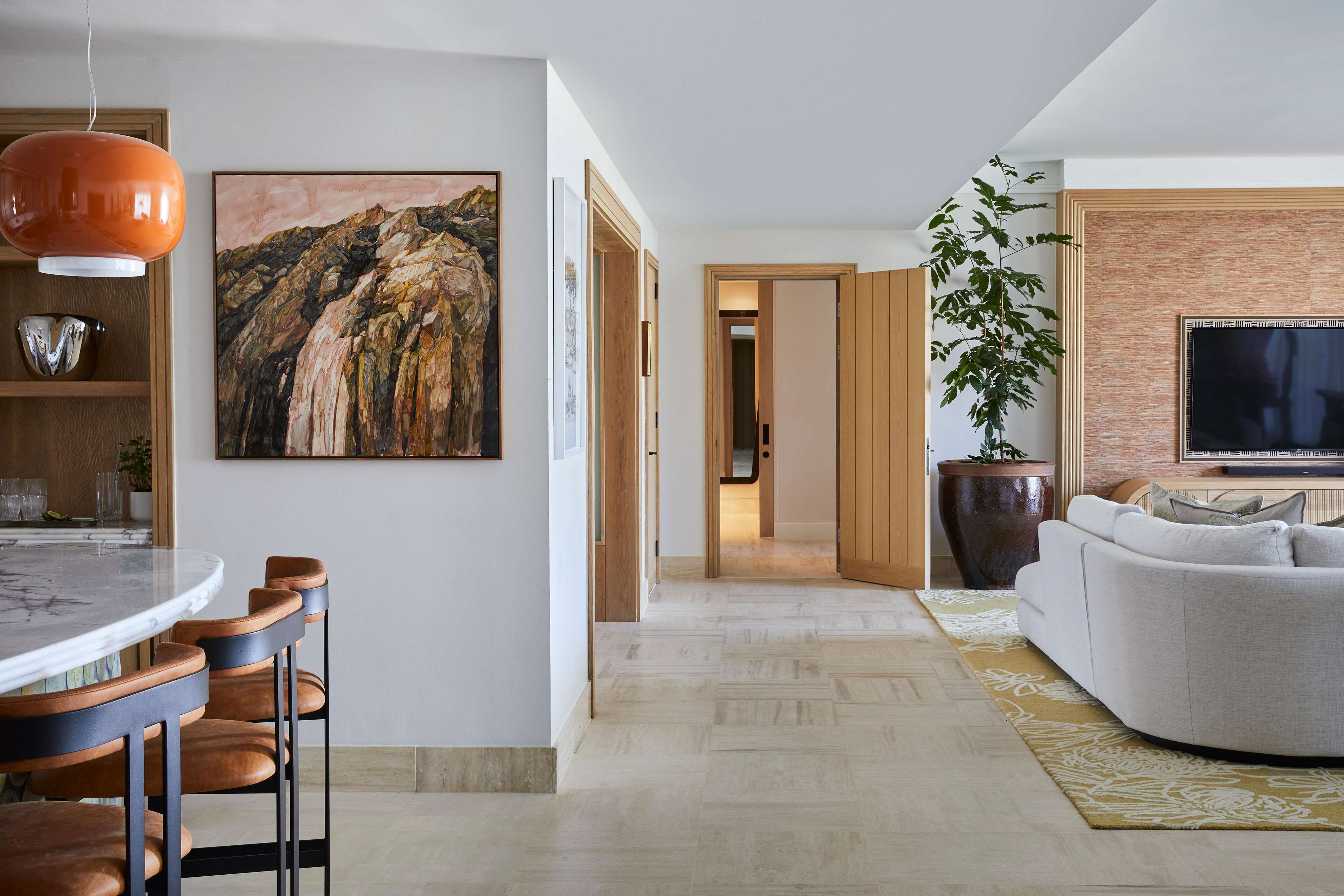 A modern living room with a sofa, a TV, and a dining area with chairs and a table.