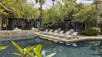 A pool area with lounge chairs and a stone wall.