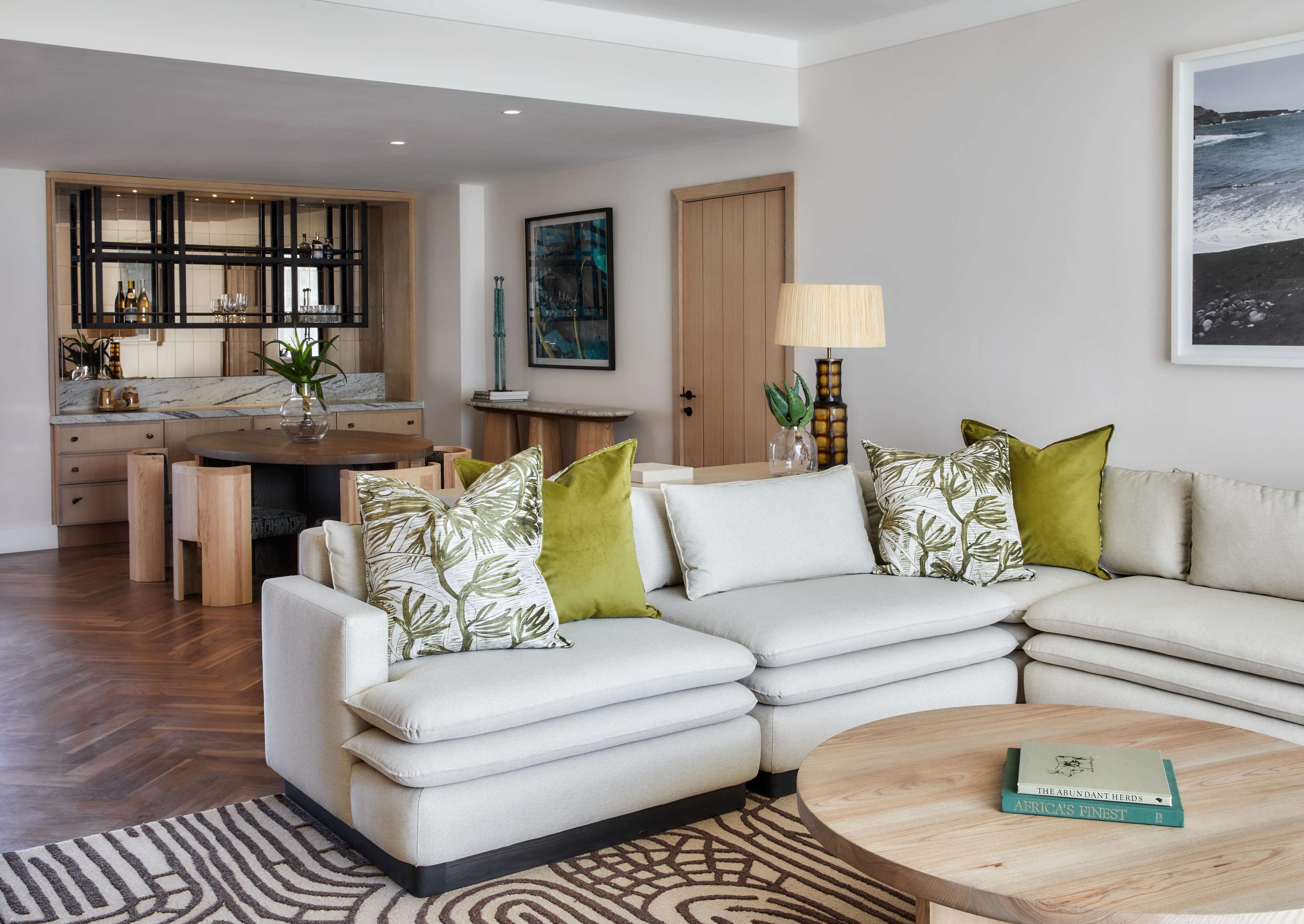 A modern living room with a sofa, a coffee table, and a dining area with a kitchen in the background.