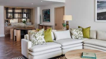 A modern living room with a sofa, a coffee table, and a dining area with a kitchen in the background.