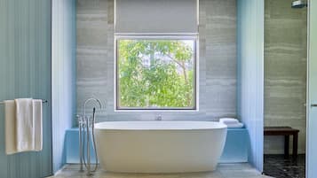 Un baño moderno con una bañera independiente, un ventanal con vistas a zonas verdes y un perchero para toallas.