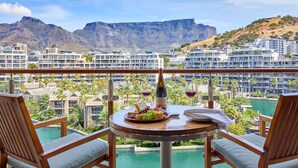 A balcony with a table set for a meal, overlooking a pool and a mountainous landscape. - One&Only Cape Town (Cape Town)
