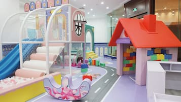 Kids can play and climb in this vibrant play area featuring a slide, climbing net, and playhouse.