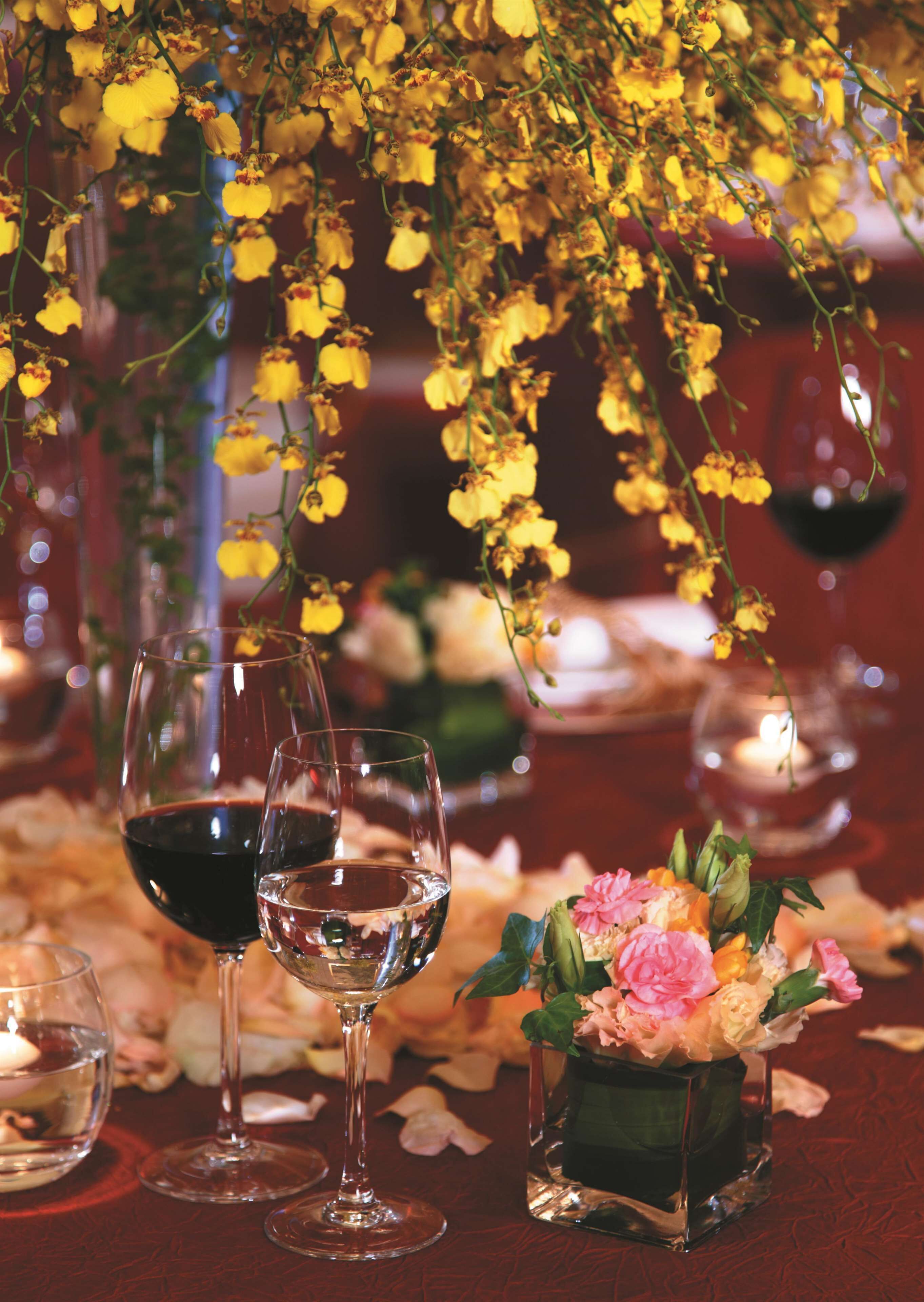 A table with wine glasses, a candle, and a vase of flowers.