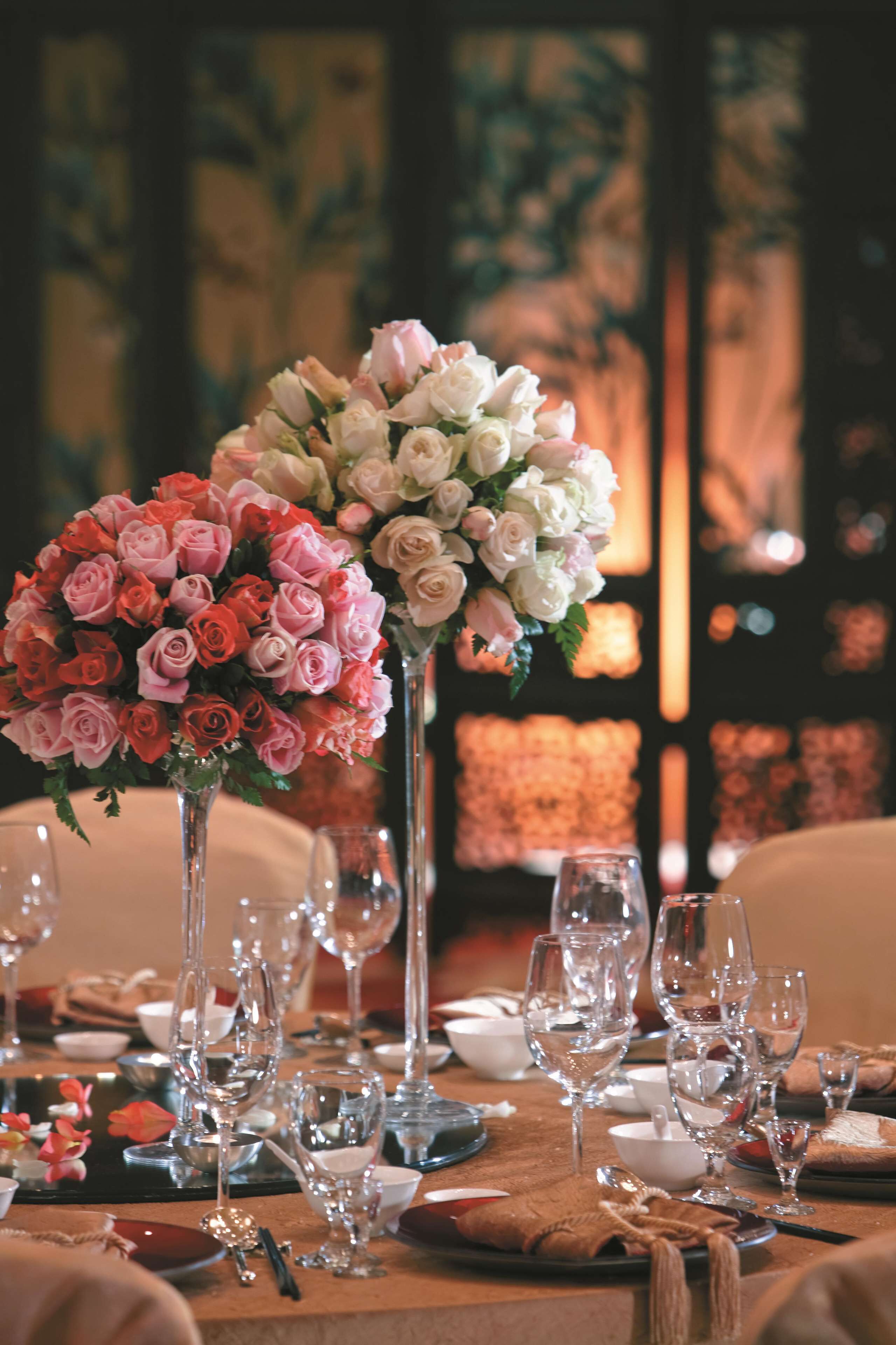 Tavola imbandita per un evento di cena elegante, con centrotavola floreale e bicchieri da vino.