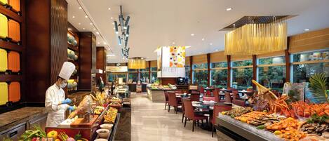 A buffet area with a variety of food items, a chef preparing food, and a dining area with tables and chairs.