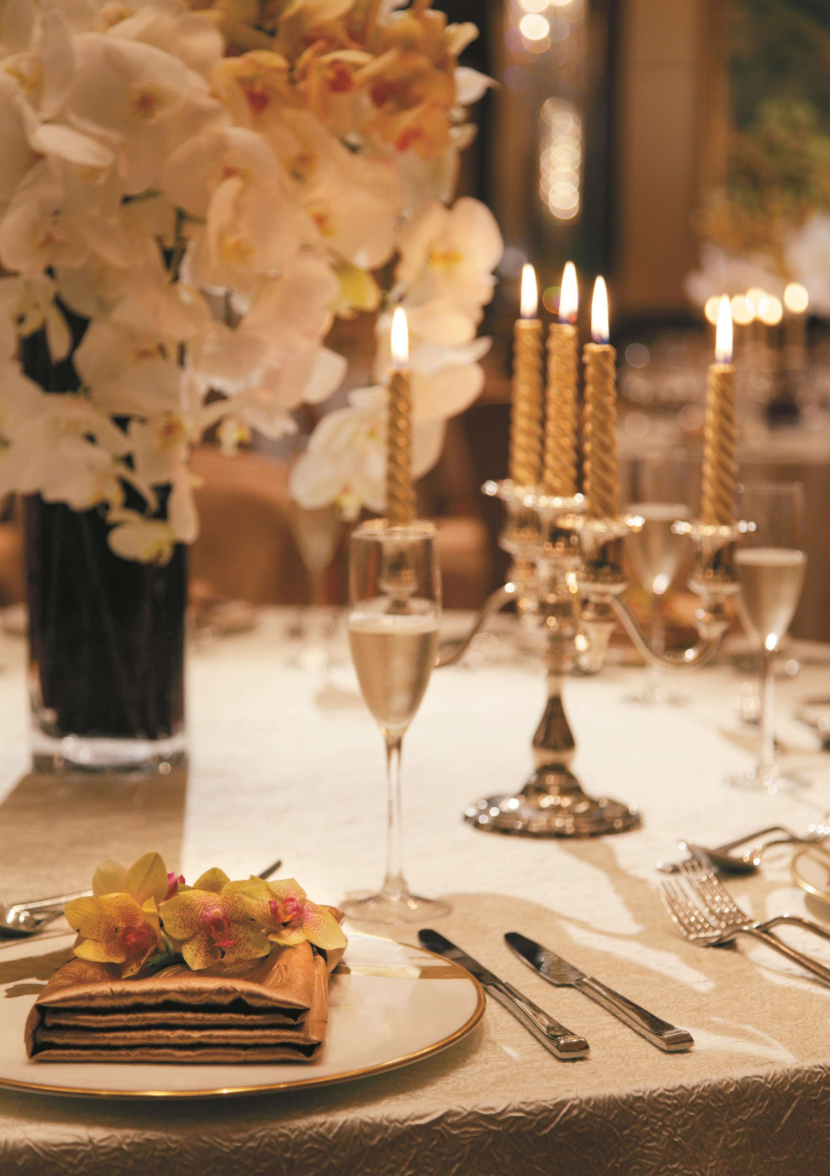 A table set with a folded napkin, a glass of champagne, and a candelabra with lit candles.