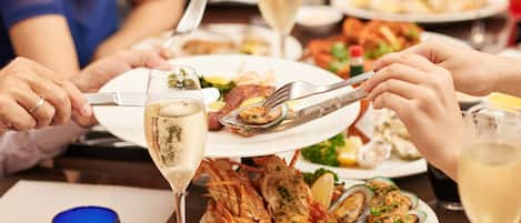A dining table with seafood dishes, wine glasses, and utensils.
