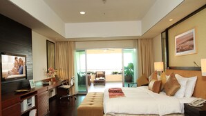Una habitación de hotel moderna con una cama grande, un escritorio con computadora, televisión y un balcón con vistas.